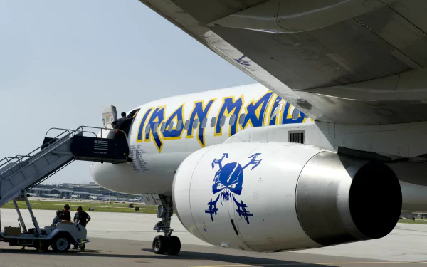 A vibrant 4K Ultra HD wallpaper featuring an Iron Maiden-branded airplane, showcasing the distinctive logo and artwork as crew members prepare for boarding on the tarmac.