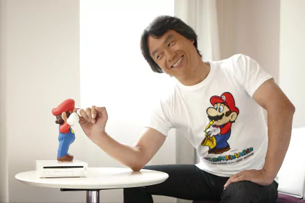 HD wallpaper featuring a smiling person with a Mario figurine on a table, reflecting a playful and creative atmosphere.