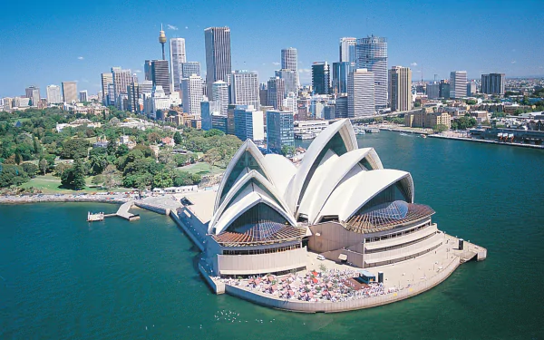 Aerial view of the Sydney Opera House set against the city skyline and harbor, captured in a vibrant HD desktop wallpaper showcasing this iconic man-made landmark.