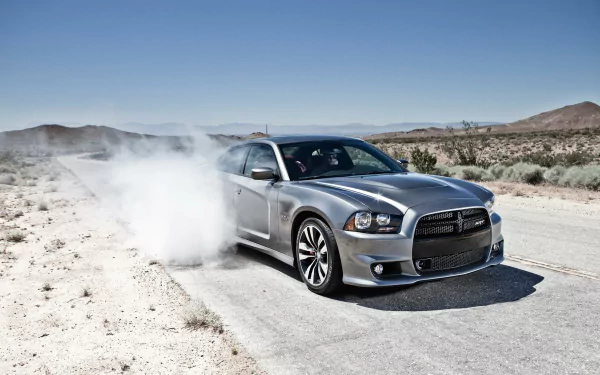 Silver Dodge Charger kicking up dust on a desert road — HD PC desktop wallpaper and vehicle background.