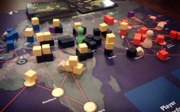 HD desktop wallpaper of the board game Pandemic with colorful game pieces spread across a world map board.