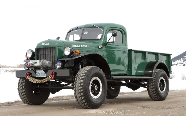 HD desktop wallpaper featuring a classic green Dodge Power Wagon truck with off-road tires against a snowy background.
