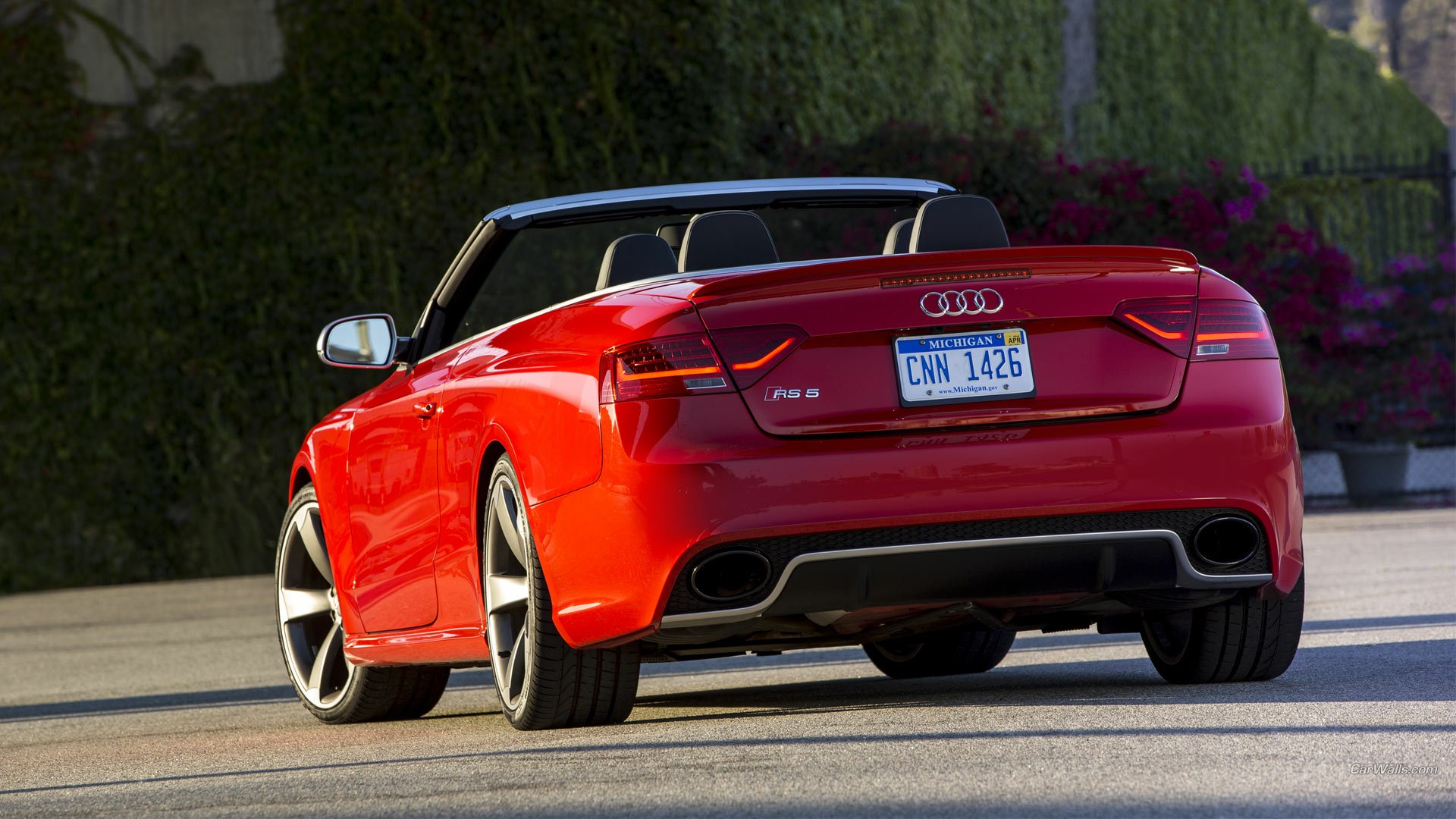 Red Audi RS5 cabriolet vehicle, rear three-quarter view on a sunlit street - HD PC desktop wallpaper and background of a sporty convertible.