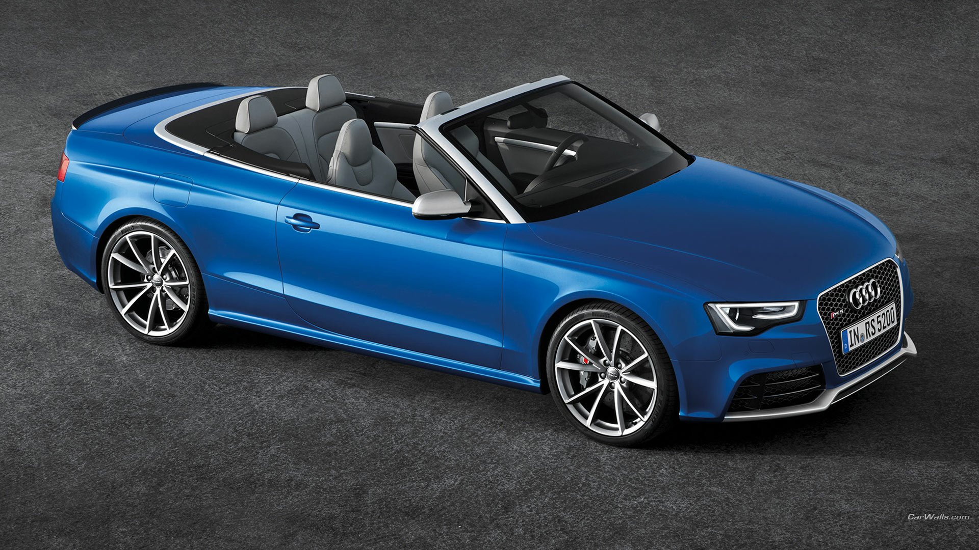 HD desktop wallpaper featuring a blue Audi RS5 convertible sports car parked on a dark textured surface.