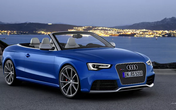 HD PC desktop wallpaper featuring a sleek blue Audi RS5 convertible parked near a body of water with city lights and hills in the background at dusk.