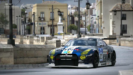 Gran Turismo 6 video game HD PC desktop wallpaper: blue-liveried racing car on a sunlit Mediterranean town street with stone buildings, lamp posts and a plaza in the background.