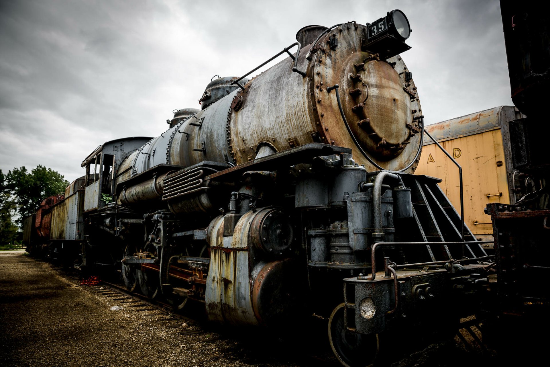 HD desktop wallpaper featuring a detailed close-up of an old, weathered steam train under a cloudy sky.