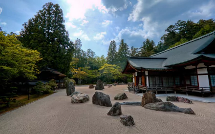 HD PC desktop wallpaper of a man-made rock garden with carefully arranged stones, surrounded by trees and traditional wooden architecture under a partly cloudy sky.