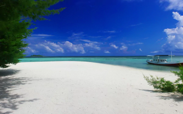 4K Ultra HD desktop wallpaper featuring a serene beach with white sand, clear turquoise water, a boat anchored near the shore, and a bright blue sky with scattered clouds.