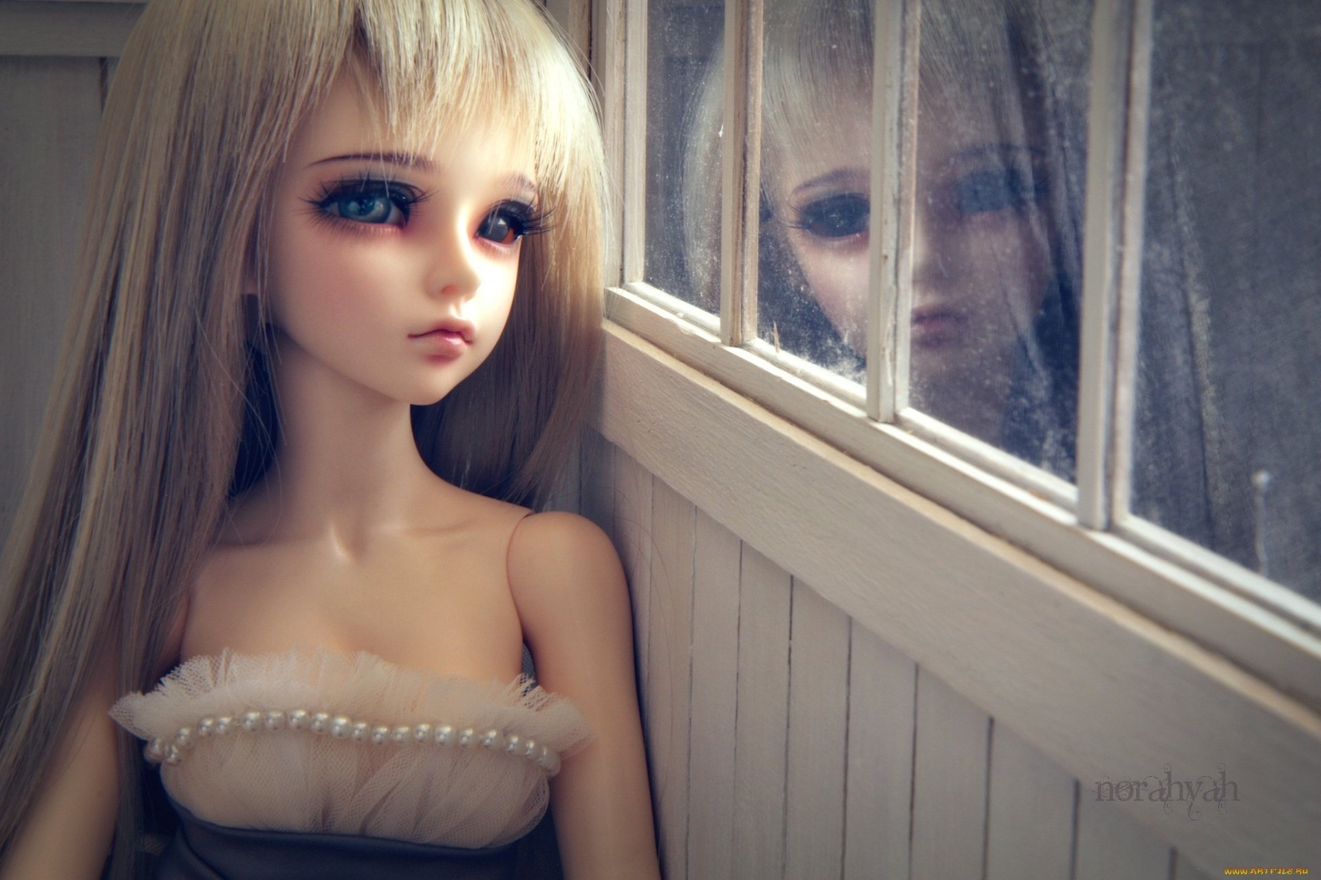 HD PC desktop wallpaper of a man-made doll with long blonde hair gazing thoughtfully by a window, her reflection softly visible on the glass.