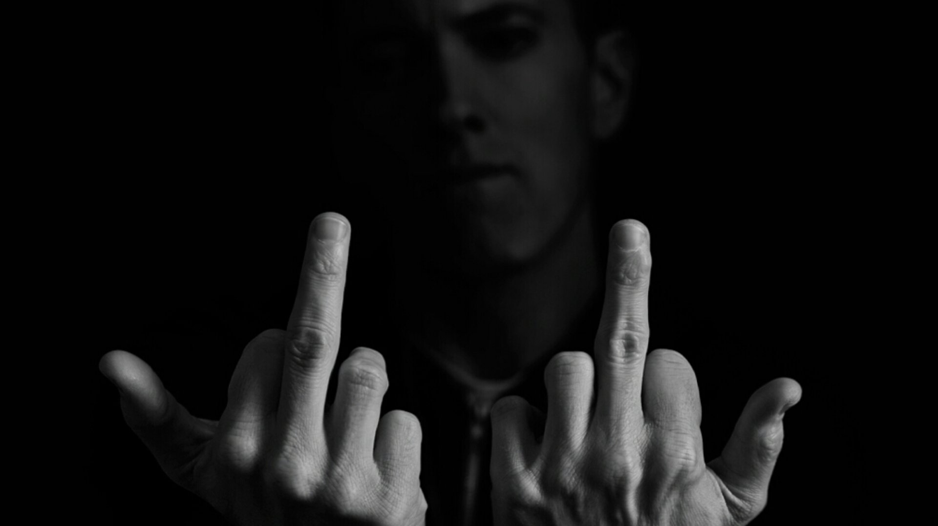 A striking black and white HD wallpaper featuring Eminem, showing him with a defiant gesture in a dramatic pose against a dark background.