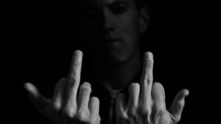 A striking black and white HD wallpaper featuring Eminem, showing him with a defiant gesture in a dramatic pose against a dark background.