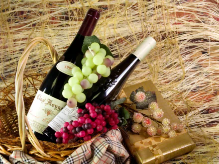 HD desktop wallpaper featuring two wine bottles, clusters of green and red grapes, and a box of chocolates arranged on a rustic straw background.