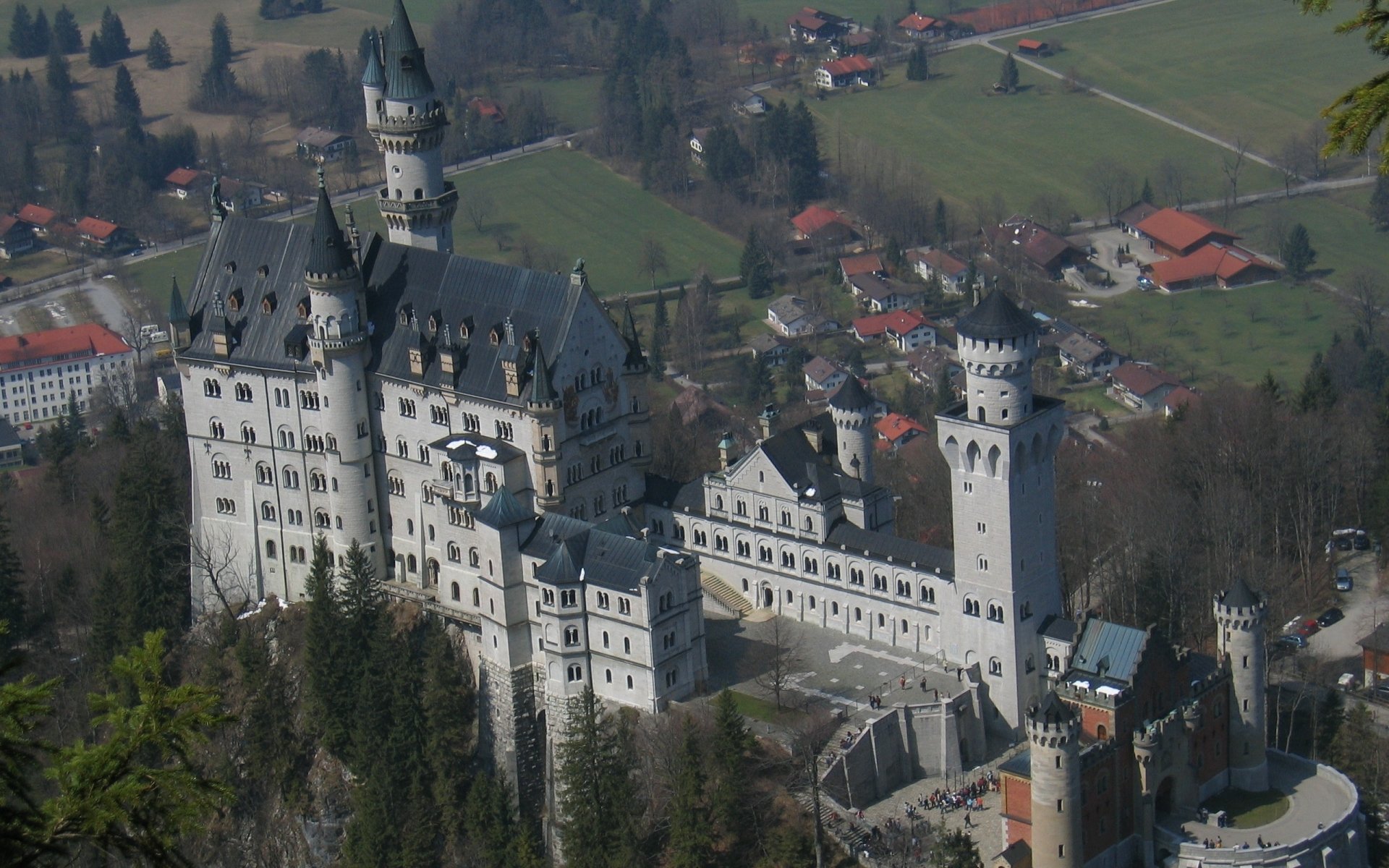 Aerial view of the man-made Neuschwanstein Castle surrounded by forest and village, captured in HD for a stunning PC desktop wallpaper and background.