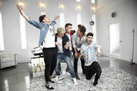 HD desktop wallpaper featuring the music band One Direction in a playful, energetic pose in a modern, well-lit room.