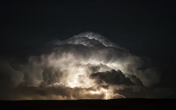 HD desktop wallpaper of a dramatic cloud illuminated by lightning, showcasing a powerful natural light display against a dark sky.