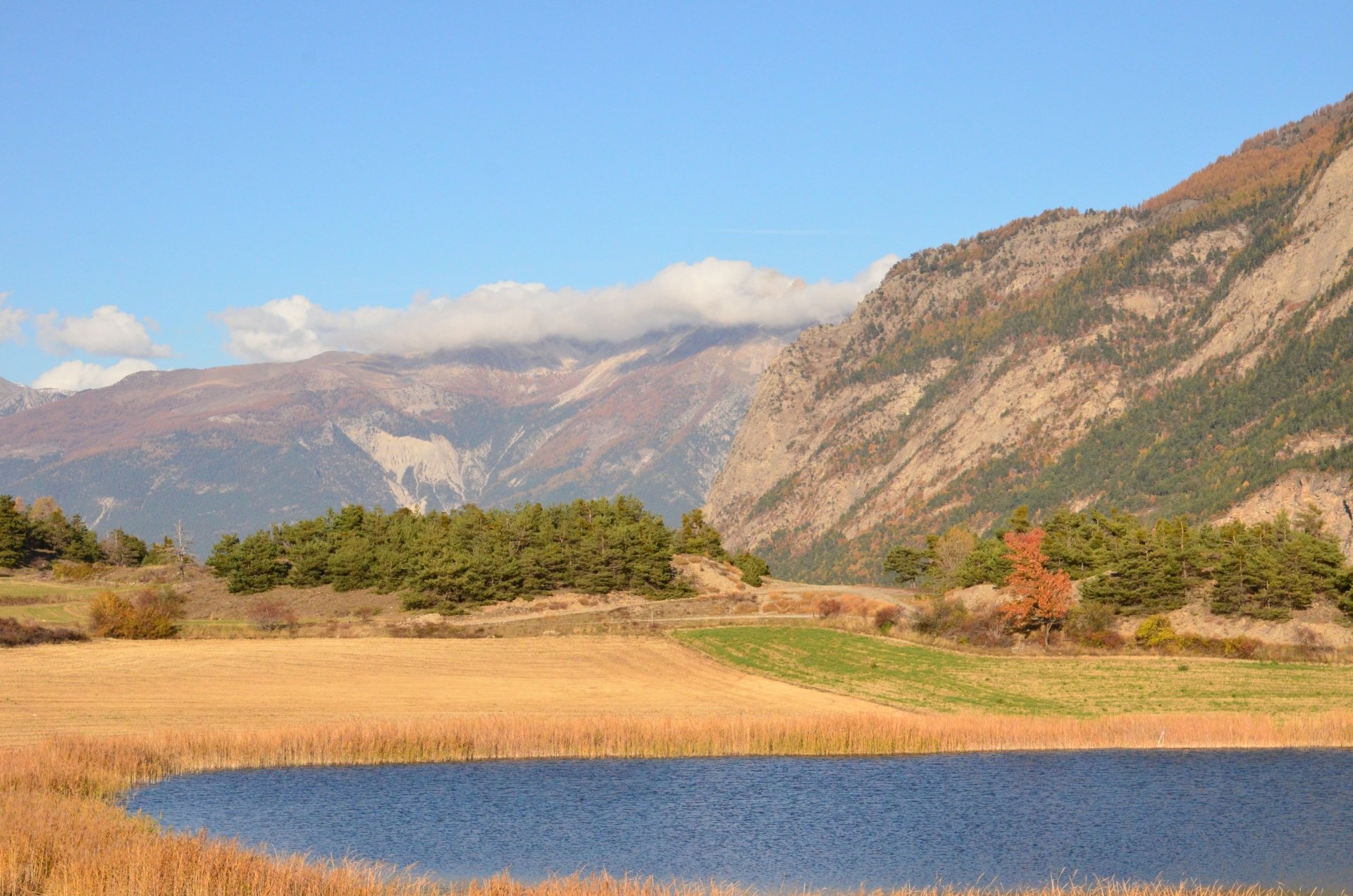 4K Ultra HD desktop wallpaper featuring a serene fall landscape with golden fields, a calm blue lake, and majestic mountains under a bright sky.