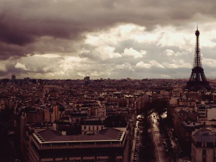 A stunning HD desktop wallpaper showcasing a panoramic view of Paris, featuring the iconic Eiffel Tower amidst a moody sky and sprawling cityscape.