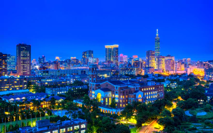 HD desktop wallpaper showcasing the vibrant man-made skyline of Taipei at dusk, featuring illuminated buildings and the iconic Taipei 101 tower against a deep blue sky.