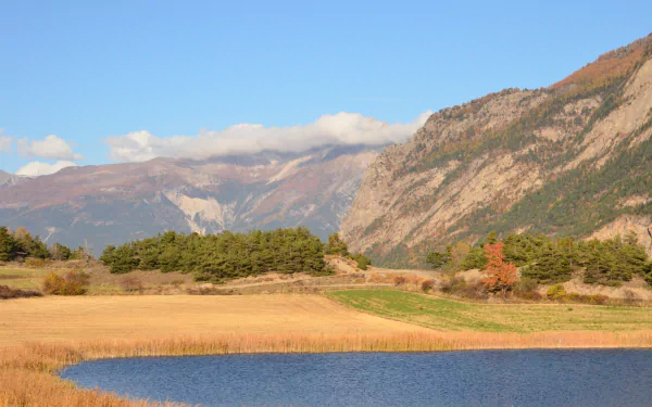 4K Ultra HD desktop wallpaper featuring a serene fall landscape with golden fields, a calm blue lake, and majestic mountains under a bright sky.