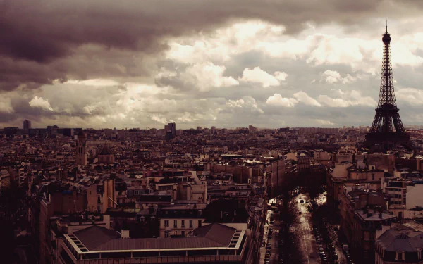 A stunning HD desktop wallpaper showcasing a panoramic view of Paris, featuring the iconic Eiffel Tower amidst a moody sky and sprawling cityscape.