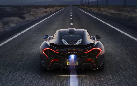 HD wallpaper of a black McLaren P1 supercar speeding on a highway, showcasing its dynamic design and powerful performance.
