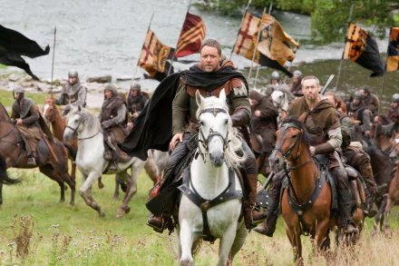 HD PC desktop wallpaper from the movie Robin Hood (2010): Robin Hood rides a white horse leading armed men across a riverside field.