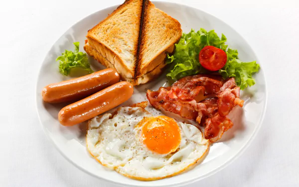 A delicious breakfast plate featuring a fried egg, crispy bacon, sausages, toast, and fresh salad, presented in vibrant detail for an enticing HD desktop wallpaper.