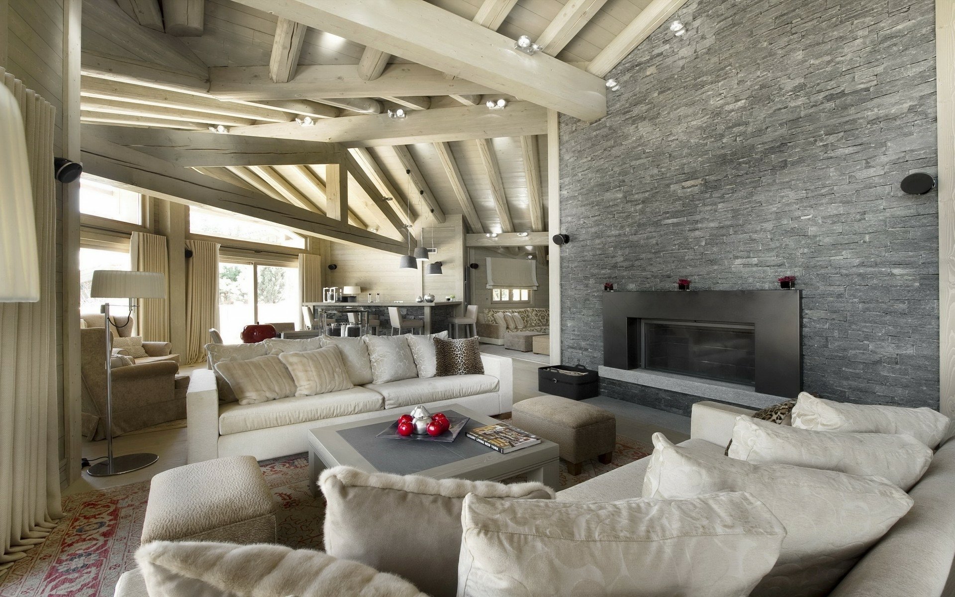 HD PC desktop wallpaper of a modern living room with plush sofas, exposed wooden beams and stone fireplace — man made room in neutral tones.