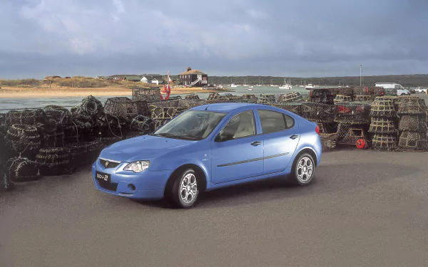 HD PC desktop wallpaper showing a blue Proton sedan parked on a coastal quay beside stacked crab traps, with calm sea and a cloudy sky in the background.