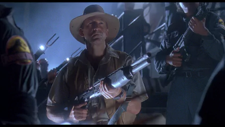 Bob Peck as Robert Muldoon stands ready with a gun in a tense scene from Jurassic Park, capturing the film's thrilling atmosphere in this HD desktop wallpaper.