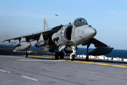 HD desktop wallpaper showing a McDonnell Douglas AV-8B Harrier II military jet on an aircraft carrier deck, with ocean and clear sky in the background.