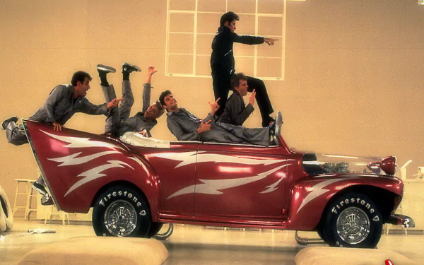 HD PC desktop wallpaper featuring a stylized vintage car with characters from the movie Grease striking dynamic poses, capturing the film's energetic vibe.