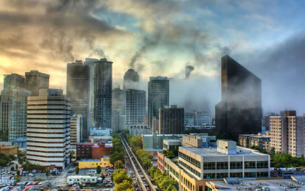 HD PC desktop background showing Seattle's man-made downtown skyline — dense high-rises, an elevated rail line and dramatic cloudy sky with mist.