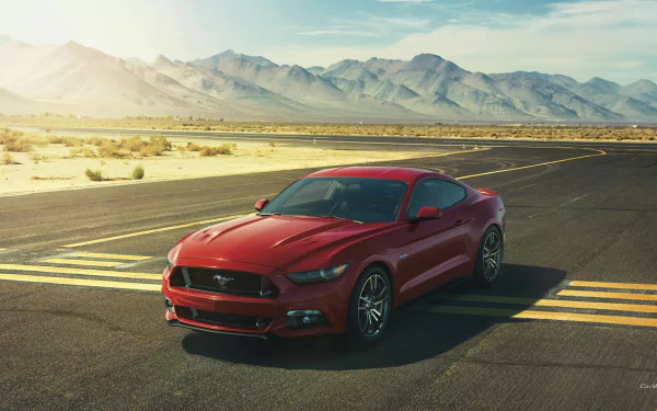 A striking 2015 Ford Mustang GT parked on a desert runway, with majestic mountains in the background. This HD image serves as a dynamic desktop wallpaper.
