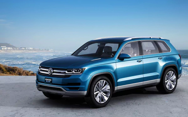 HD desktop wallpaper featuring the Volkswagen CrossBlue Hybrid Concept, a sleek blue Volkswagen SUV parked by the coast under a clear sky.