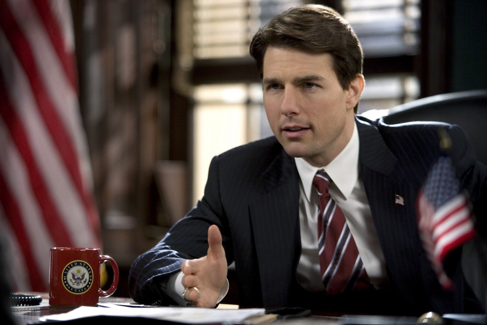 HD PC desktop wallpaper featuring a scene from the movie Lions for Lambs, showing a man in a suit speaking at a desk with American flags nearby.