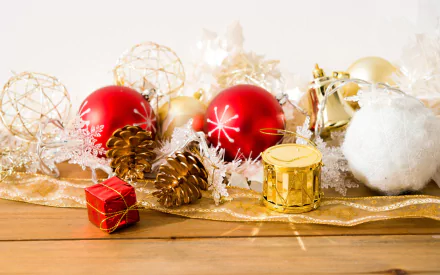 HD PC desktop wallpaper featuring Santa-themed Christmas decorations, including red ornaments, pinecones, a gift box, and festive golden accents on a wooden surface.