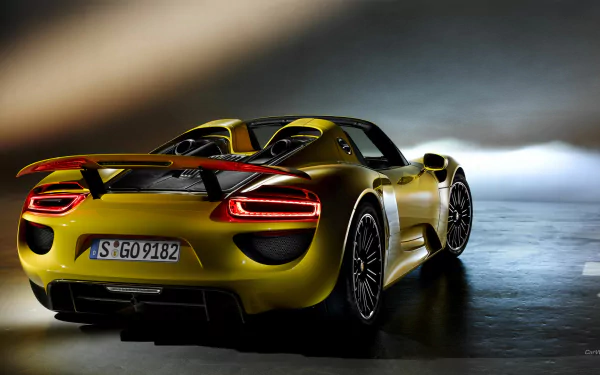 A dynamic Porsche 918 Spyder in striking yellow, showcased in an HD desktop wallpaper, highlighting its sleek design and powerful presence.