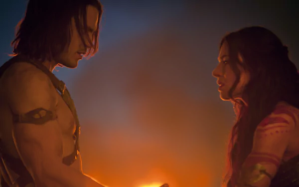 John Carter movie still: Dejah Thoris and a shirtless warrior face each other in warm firelight — 5K Ultra HD PC desktop wallpaper.