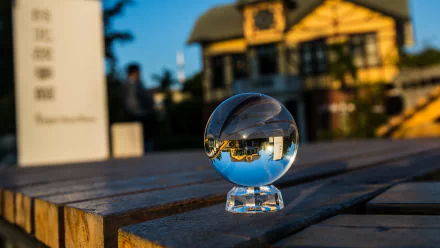 4K Ultra HD PC desktop wallpaper: crystal glass sphere on a wooden bench reflecting an inverted house and blue sky, vivid photography capturing crisp reflections.