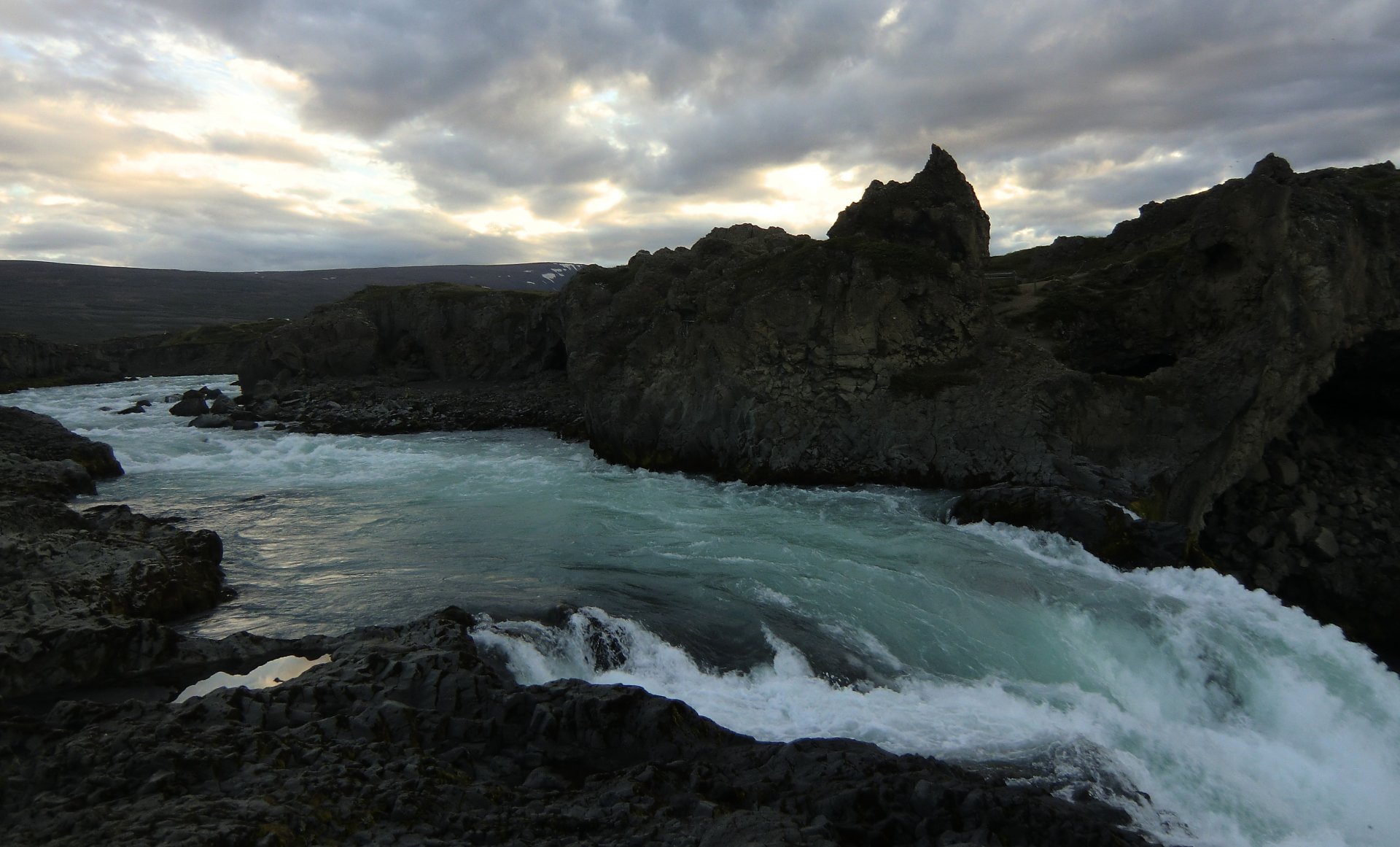 4K Ultra HD PC desktop wallpaper and background: turquoise river and rushing stream carving through rugged volcanic rocks in Iceland beneath a dramatic cloudy sky.