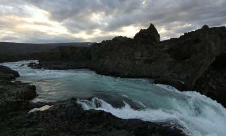 4K Ultra HD PC desktop wallpaper and background: turquoise river and rushing stream carving through rugged volcanic rocks in Iceland beneath a dramatic cloudy sky.