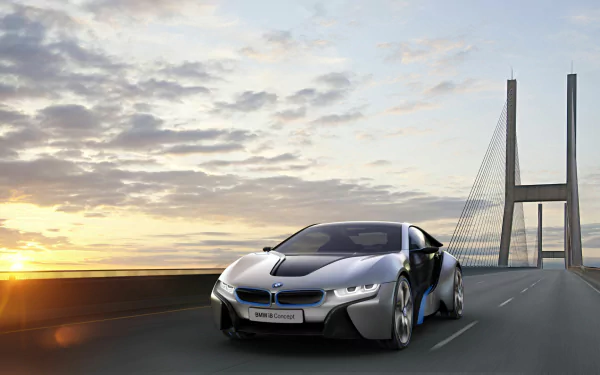 HD PC desktop wallpaper featuring a sleek silver BMW i8 driving on a modern bridge at sunset under a cloudy sky.