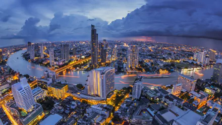HD desktop wallpaper of Bangkok at night, showcasing city lights and a river winding through Thailand's vibrant capital. The image captures a stunning man-made skyline under a twilight sky.