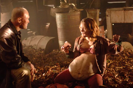 HD PC desktop wallpaper from the movie Slither, featuring two characters in a dimly lit, grim setting with a large, swollen abdomen on one figure.