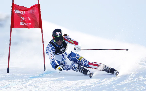 Slalom skier carving a sharp turn past a red gate on a sunlit snowy slope — sports action, 2K Quad HD PC desktop wallpaper and background.