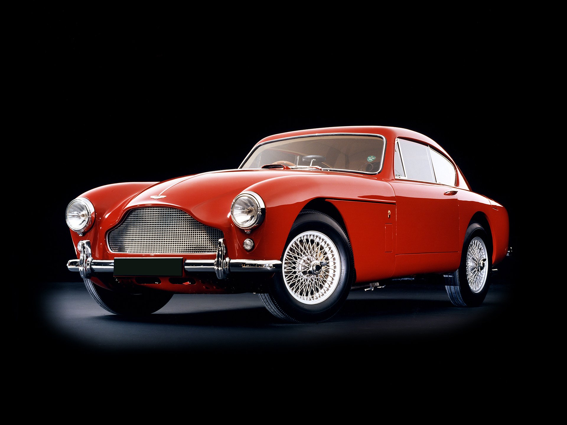 A red Aston Martin DB Mark III classic vehicle showcased on a black background, featured as an HD PC desktop wallpaper and background.