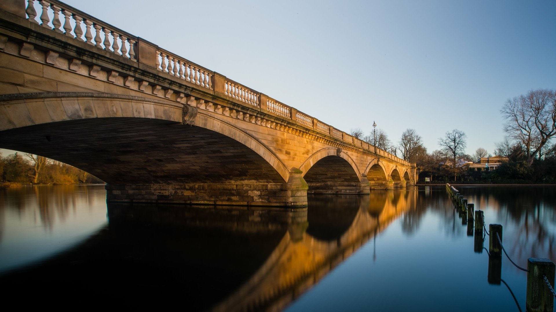 Stone Serpentine Bridge at dusk, warm light and arches mirrored in still water — 4K Ultra HD man-made bridge PC desktop wallpaper and background.