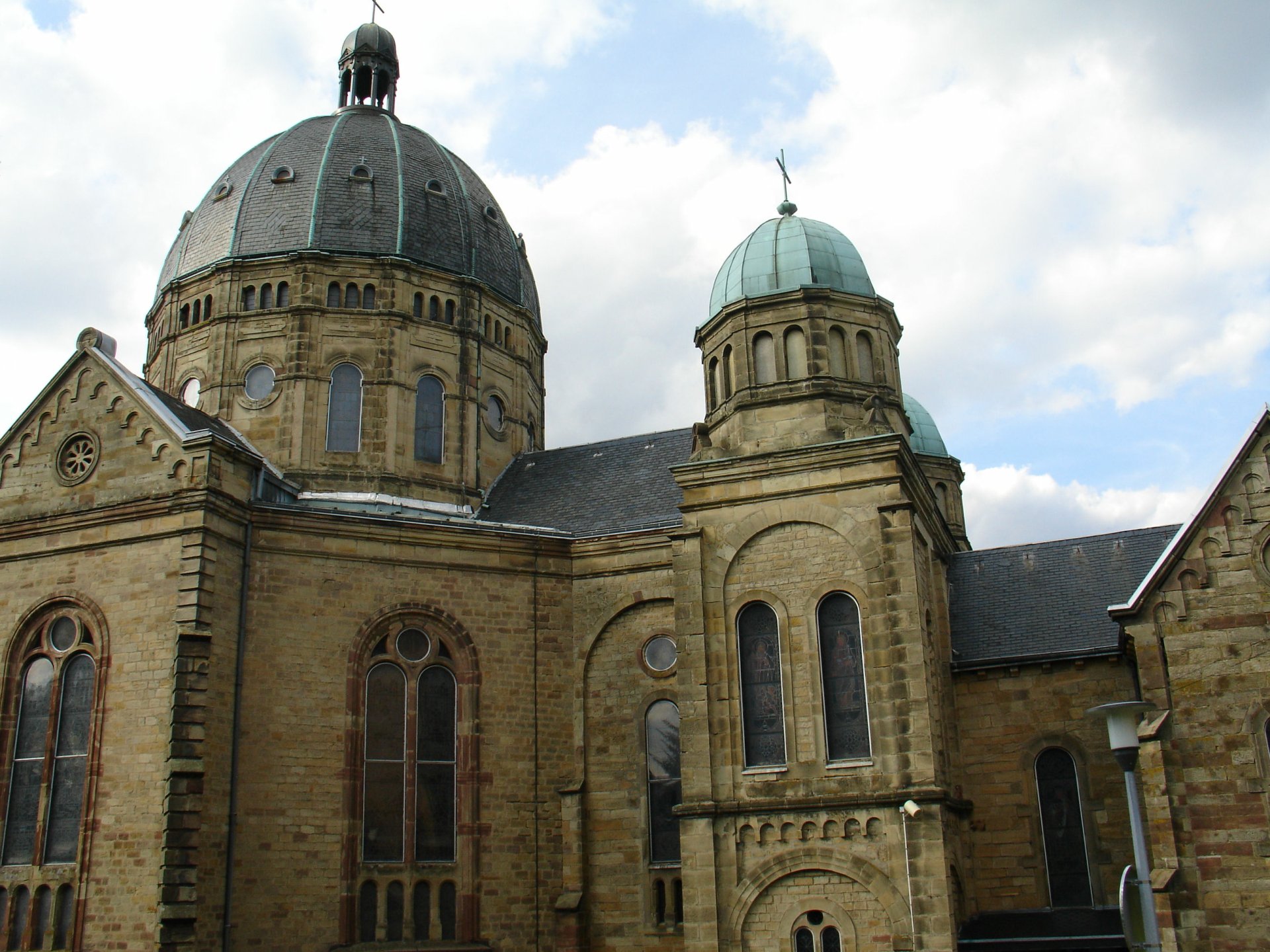 Basilique Notre-Dame de Saint-Avold: stone church with domes and arched windows against a cloudy sky — 2K Quad HD PC desktop wallpaper.